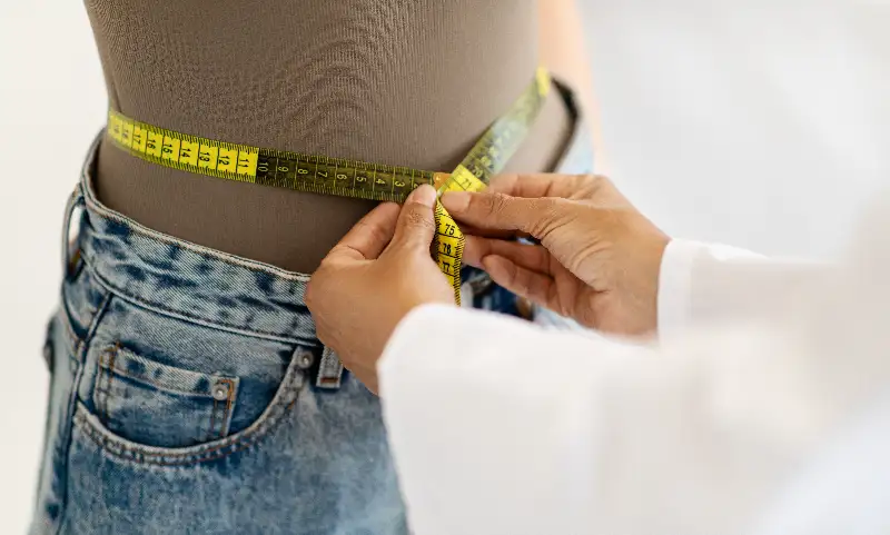 A doctor measures a patient’s waist to assess progress in a weight-loss clinic in Ponte Vedra, FL.