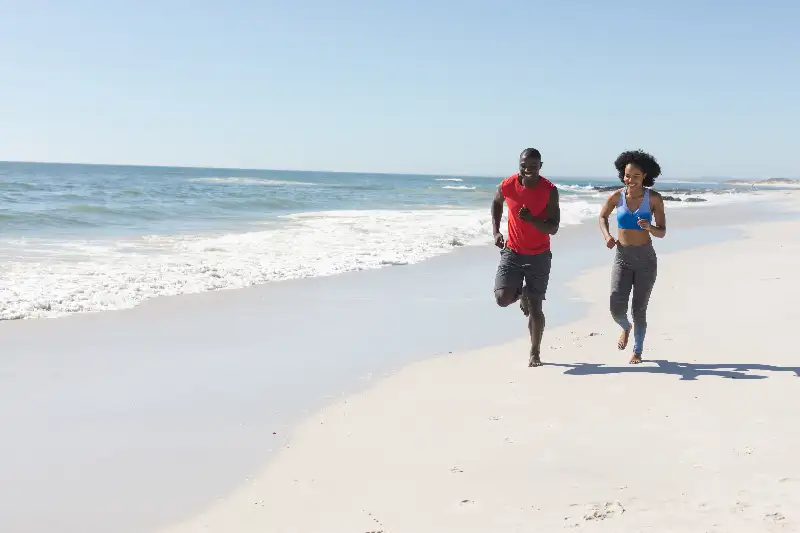 A healthy and active couple run together on the beach in Ponte Vedra, FL.