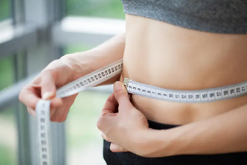 diet woman in sportswear measuring her waist