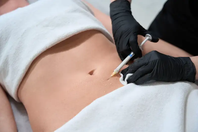 female in black gloves makes injections in belly